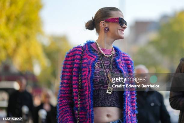 Guest wears purple pink sunglasses from Chanel, purple earrings, a white pearls / silver chain long necklace from Chanel, a black and pink wool...