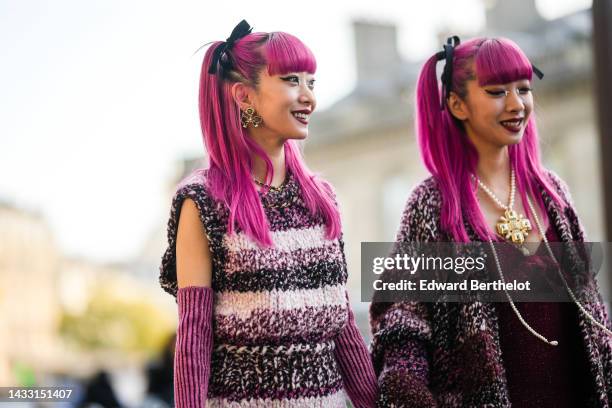 Ami wears black velvet knot hair clips, gold earrings, a gold chain and black shiny leather necklace from Chanel, a black / white / pink braided wool...