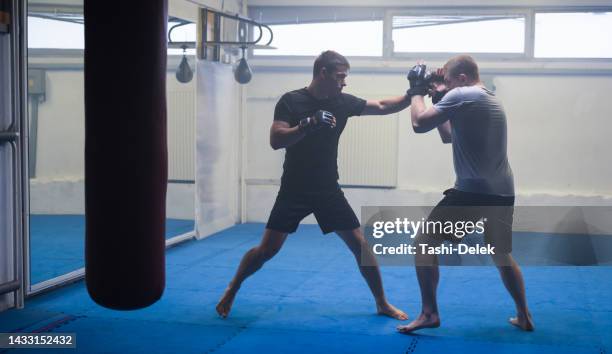 deux partenaires masculins ou mma le boxeur et l’entraîneur pratiquent des exercices de sparring pour un mode de vie de bien-être sain - fighting ring stock photos et images de collection