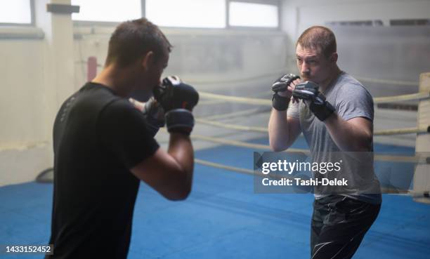 two male partners or mma boxer and trainer practice sparring exercises for a healthy wellness lifestyle - fighting ring stock pictures, royalty-free photos & images