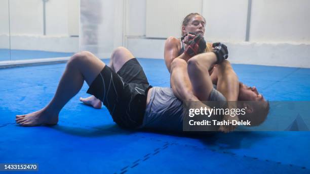 training mma and learning to fight, a male trainer and woman getting fit in gym. fitness, motivation and female empowerment. strong kick and healthy exercise, a young lady and her sports coach - women being strangled stockfoto's en -beelden