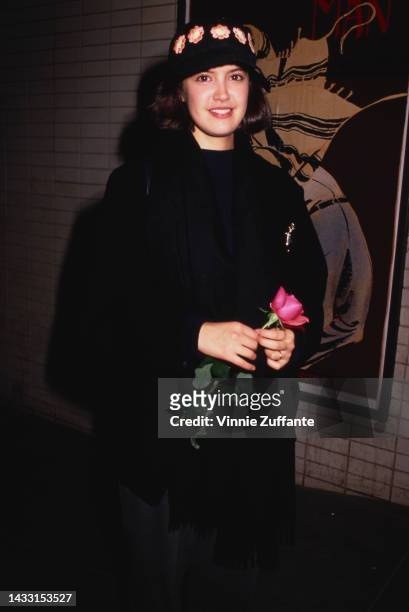 Phoebe Cates holds a rose at an unspecified event, United States, circa 1990s.