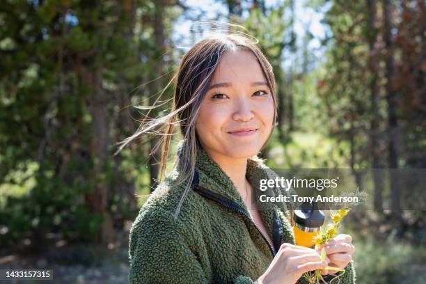 portrait of young woman outdoors with water bottle and wildflowers - close up of mushroom growing outdoors stockfoto's en -beelden