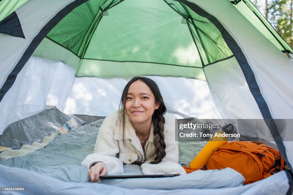 Young woman in tent with digital tablet