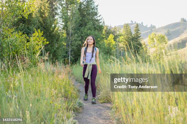 young woman hiking on mountain trail - largo longitud fotografías e imágenes de stock