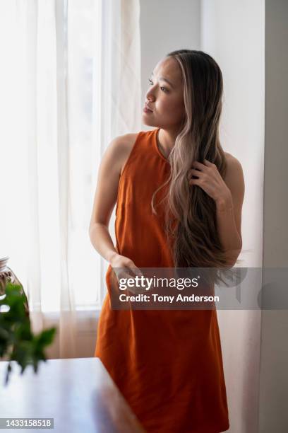 young woman fixing her hair inside home - mèche colorée photos et images de collection