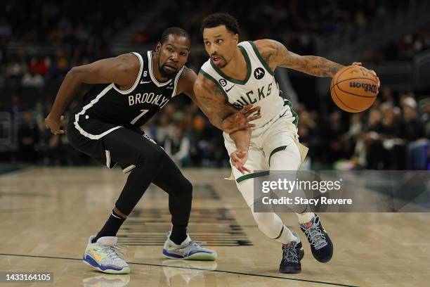 George Hill of the Milwaukee Bucks drives around Kevin Durant of the Brooklyn Nets during a preseason game at Fiserv Forum on October 12, 2022 in...