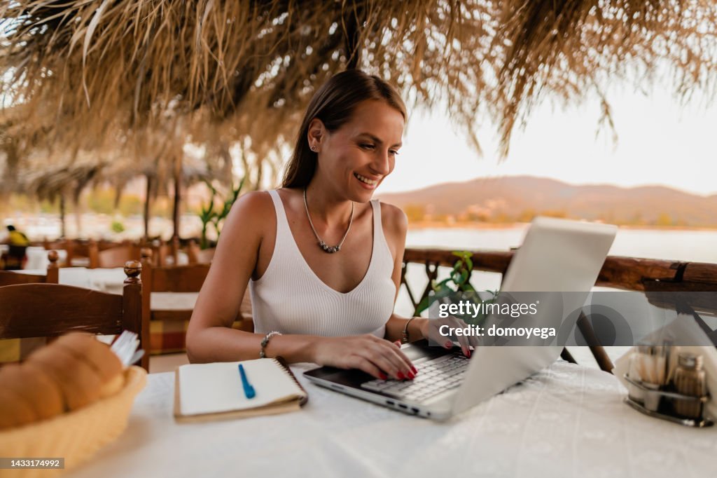 Woman learning and using a laptop in a restaurant at the seaside