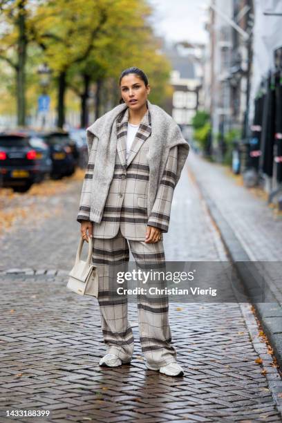 Kae Sutherland wears checkered grey latte suit Anine Bing, sweater Woolrich, jewellery 24Kae, Jacquemus bag, sneakers on October 13, 2022 in...