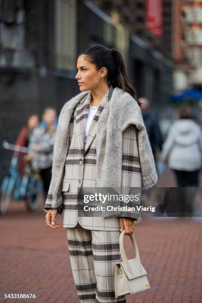 Kae Sutherland wears checkered grey latte suit Anine Bing, sweater Woolrich, jewellery 24Kae, Jacquemus bag, sneakers on October 13, 2022 in...