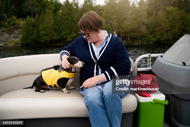 senior woman and a dog enjoying a pontoon boat tour on a lake in autumn. - dachshund holiday stock pictures, royalty-free photos & images