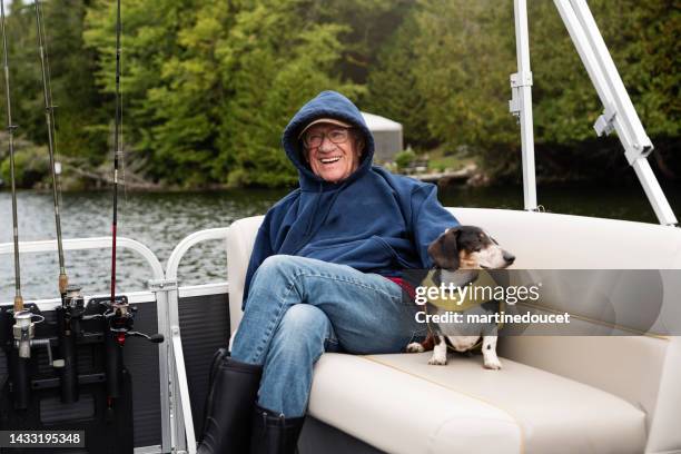 senior man and a dog enjoying a pontoon boat tour on a lake in autumn. - pontoon boat stock pictures, royalty-free photos & images