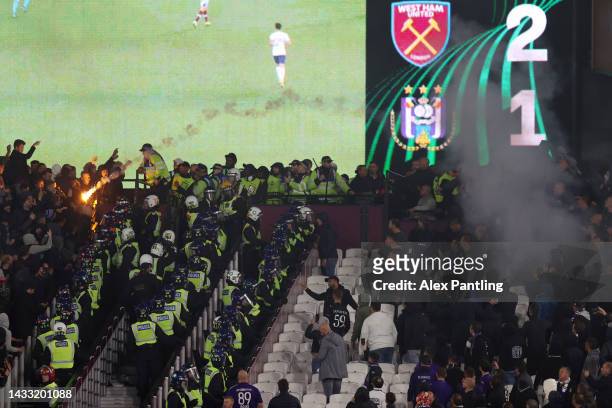 Police are seen separating West Ham United and Anderlecht fans as flares are thrown during the UEFA Europa Conference League group B match between...