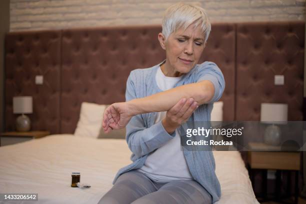 リウマチに苦しむ手首と腕をこすっている女性 - knuckle ストックフォトと画像