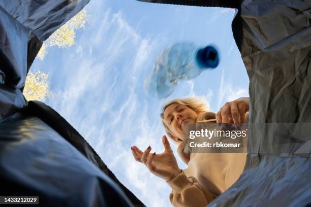 used plastic bottle falling into a trash can - white trash stock-fotos und bilder