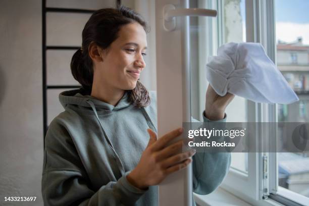 young woman cleaning and wiping window - window cleaner stock pictures, royalty-free photos & images