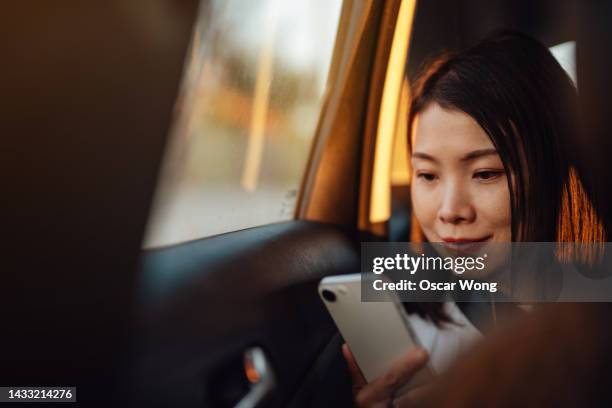 young asian woman using smart phone in a car - white collar worker dawn light stock pictures, royalty-free photos & images