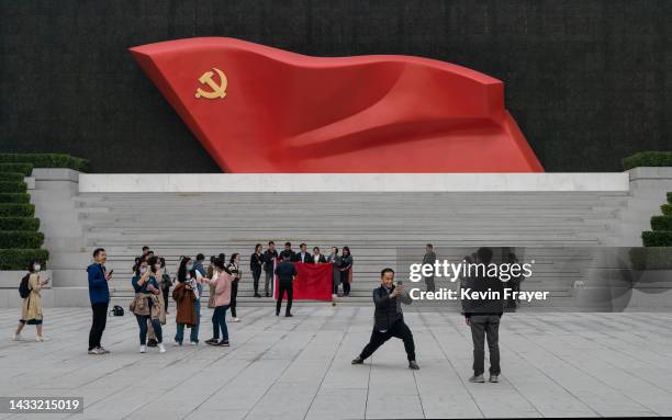 Visitors take photos and gather in front of a large display showing the Communist Party flag, outside the Museum of the Communist Party, on October...