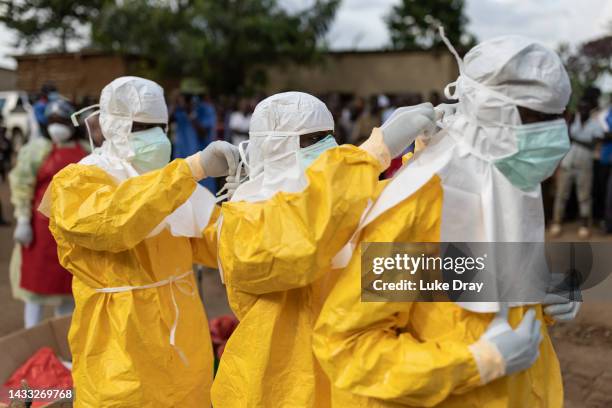 Red Cross workers don PPE prior to burying a 3-year-old boy suspected of dying from Ebola on October 13, 2022 in Mubende, Uganda. Emergency response...