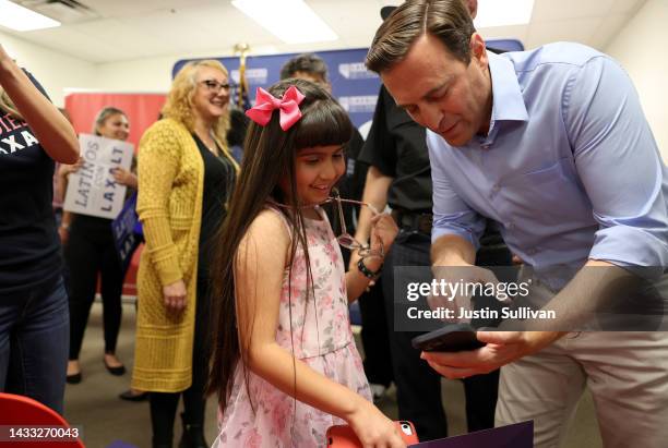 Nevada Republican U.S. Senate candidate Adam Laxalt shows a picture of his daughter to a young girl during a Hispanic Heritage Month Fiesta at the...