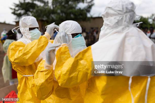 Red Cross workers don PPE prior to burying a 3-year-old boy suspected of dying from Ebola on October 13, 2022 in Mubende, Uganda. Emergency response...