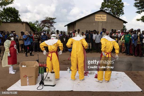 Red Cross workers don PPE prior to burying a 3-year-old boy suspected of dying from Ebola on October 13, 2022 in Mubende, Uganda. Emergency response...