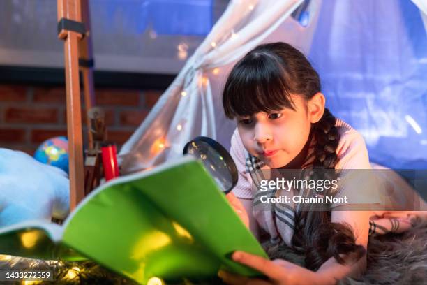 cute girl reading a book on the bed under the tent at night, education and book lovers, lifestyle - nursery night stock pictures, royalty-free photos & images