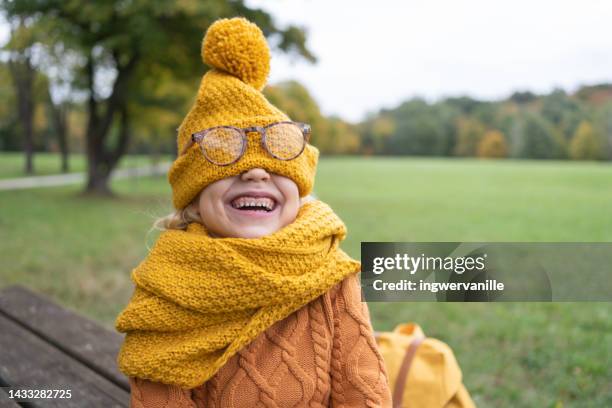 laughing girl covering her face with knitted hat in a park - 5 funny foto e immagini stock