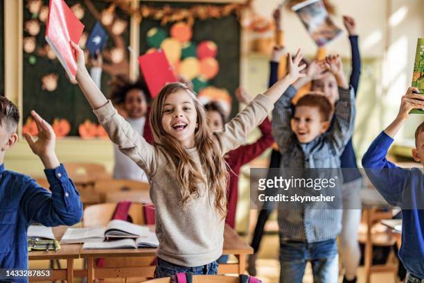 playful elementary students jumping with raised arms in the classroom. - children only stock pictures, royalty-free photos & images