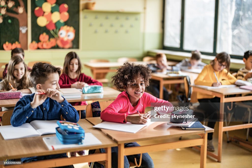 Happy elementary students having a class in the classroom.
