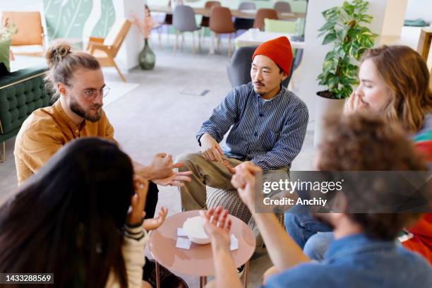 multi ethnic group of coworkers playing game of rock paper scissors - rock paper scissors stock pictures, royalty-free photos & images