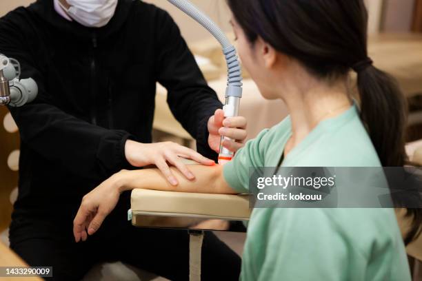 physical therapist treating female patient with electro therapy at medical clinic. - infrared lamp stock pictures, royalty-free photos & images