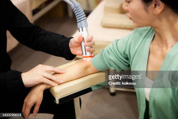 physical therapist treating female patient with electro therapy at medical clinic. - infrared lamp 個照片及圖片檔