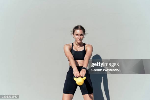 young woman exercising with kettlebell on sunny day - krafttraining stock-fotos und bilder