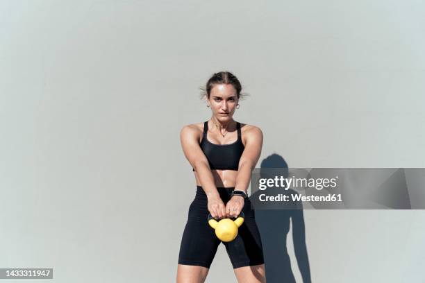 young woman exercising with kettlebell on sunny day - strength training stock pictures, royalty-free photos & images