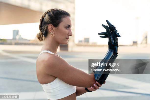 beautiful young woman looking at arm prosthesis - robotics stockfoto's en -beelden