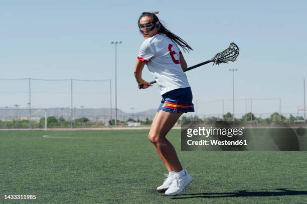 player with lacrosse stick playing on sports field - lacrosse stock-fotos und bilder