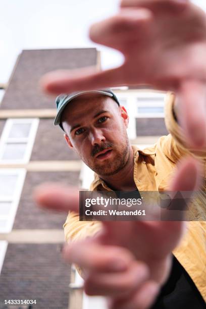 man gesturing finger frame in front of building - dedos fazendo moldura - fotografias e filmes do acervo