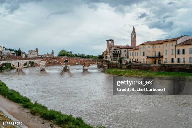 the roman ponte pietra in verona under adiglio river with the basilica of saint anastasia bell tower on the right. - véneto bildbanksfoton och bilder