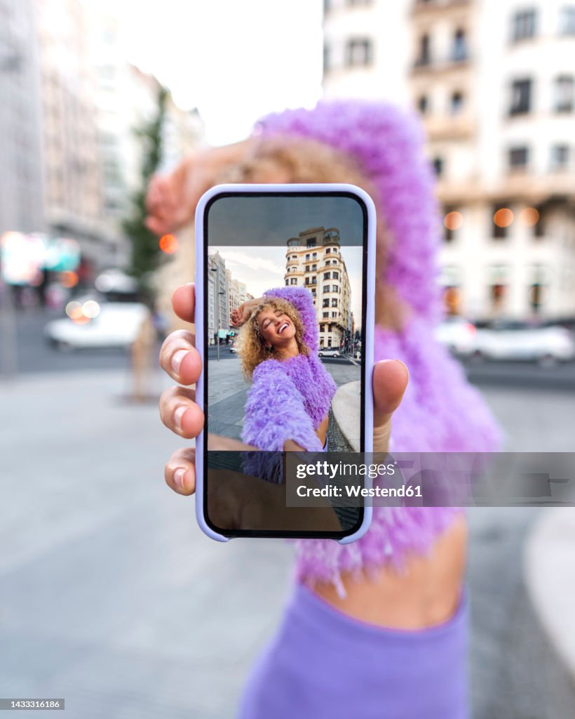 Young woman showing selfie on smart phone