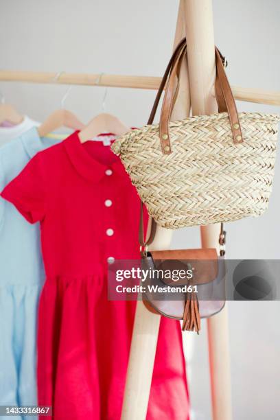 sling bag and handbag on clothes rack in store - red dress stock pictures, royalty-free photos & images