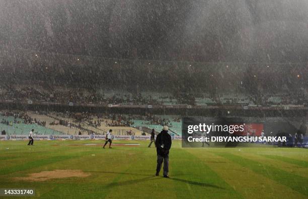 Indian groundsmen cover the pitch as the IPL Twenty20 cricket match between Deccan Chargers and Kolkata Knight Riders is delayed due to rain at The...