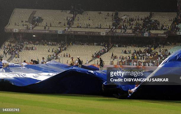 Indian groundsmen cover the pitch as the IPL Twenty20 cricket match between Deccan Chargers and Kolkata Knight Riders is delayed due to rain at The...