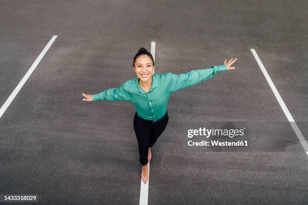 happy businesswoman with arms outstretched balancing on road marking - 腕を広げる ストックフォトと画像