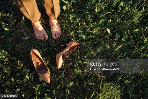 businesswoman standing by brown stilettos on grass in park - tacchi a spillo foto e immagini stock