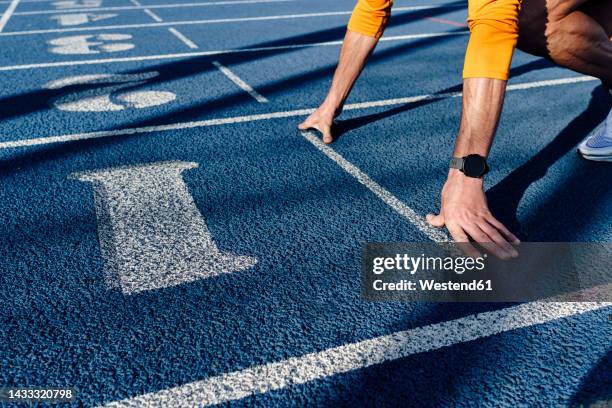 sportsman at starting line of running track - comienzo fotografías e imágenes de stock