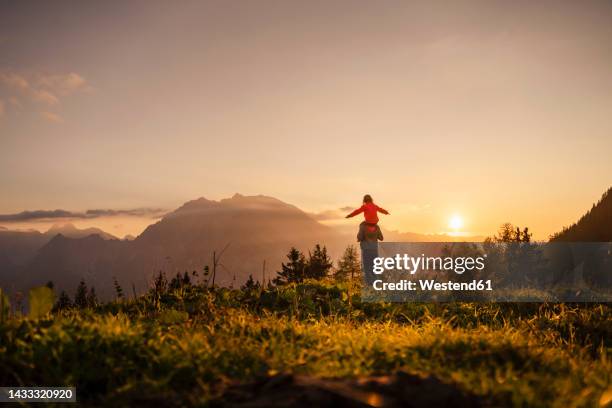 woman carrying daughter on shoulder standing at mountain - piggy back stockfoto's en -beelden