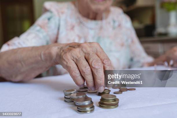 senior woman stacking coins on table at home - money piling up stock pictures, royalty-free photos & images
