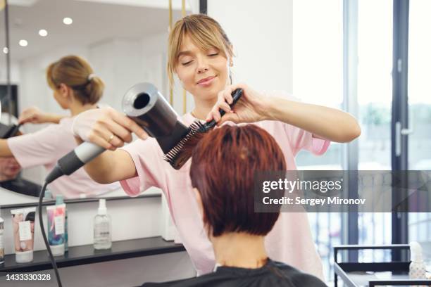 hairstylist working with client hairs with hairdryer - haircutting scissors stock pictures, royalty-free photos & images