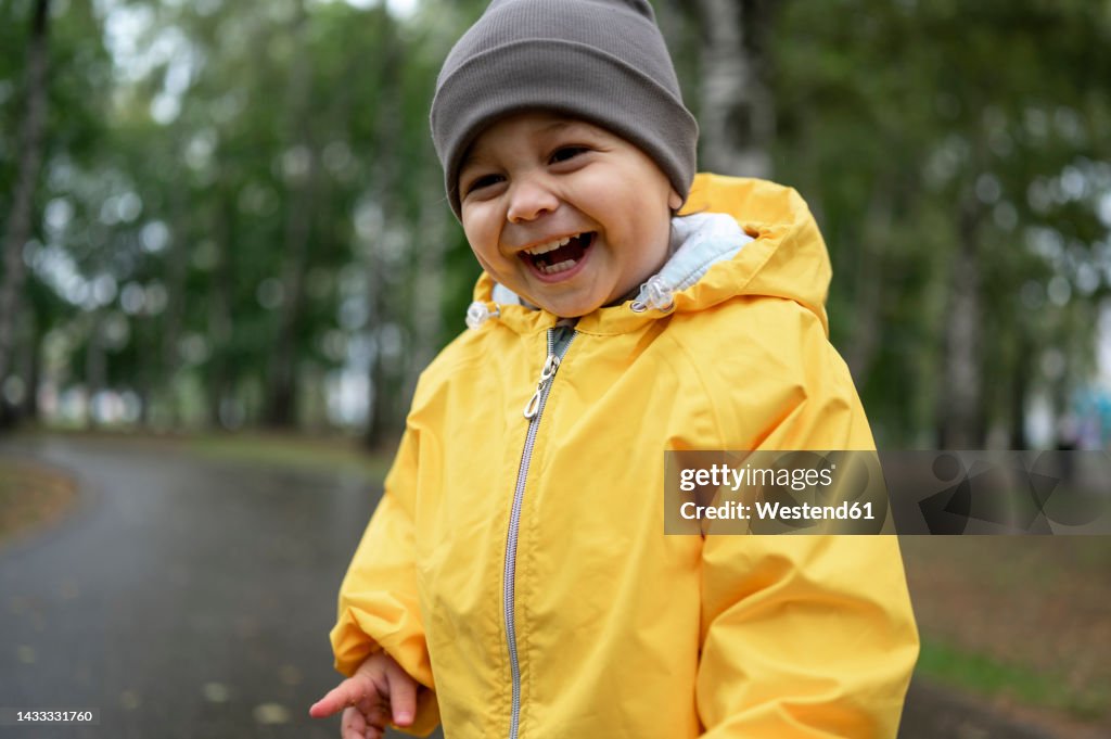 Cute happy boy wearing knit hat and yellow rain jacket